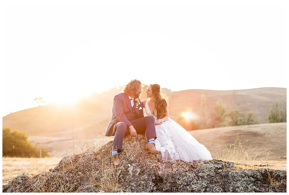 A couple on hay bales bathed in golden sunset light at Glenn Ranch