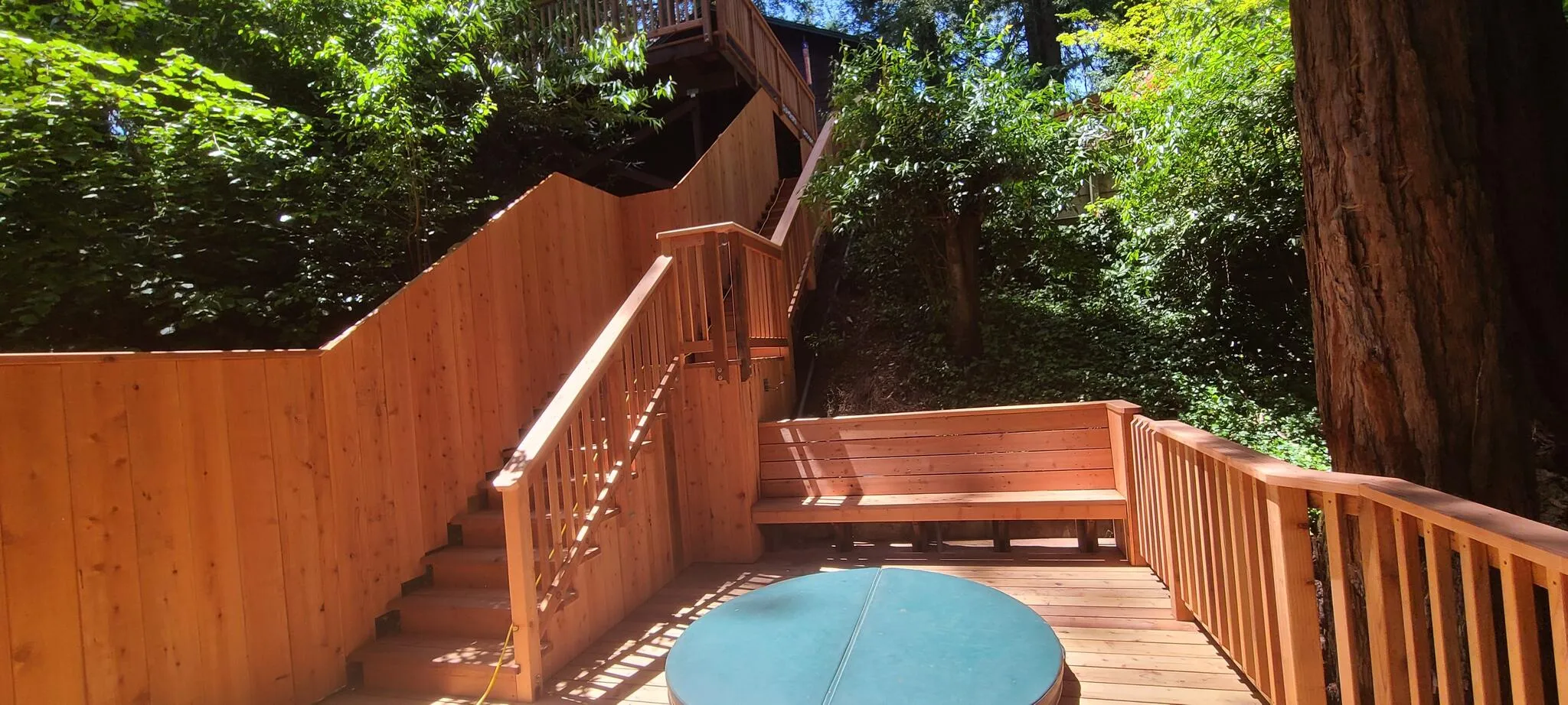 Redwood deck with hot tub and bench seating set among trees