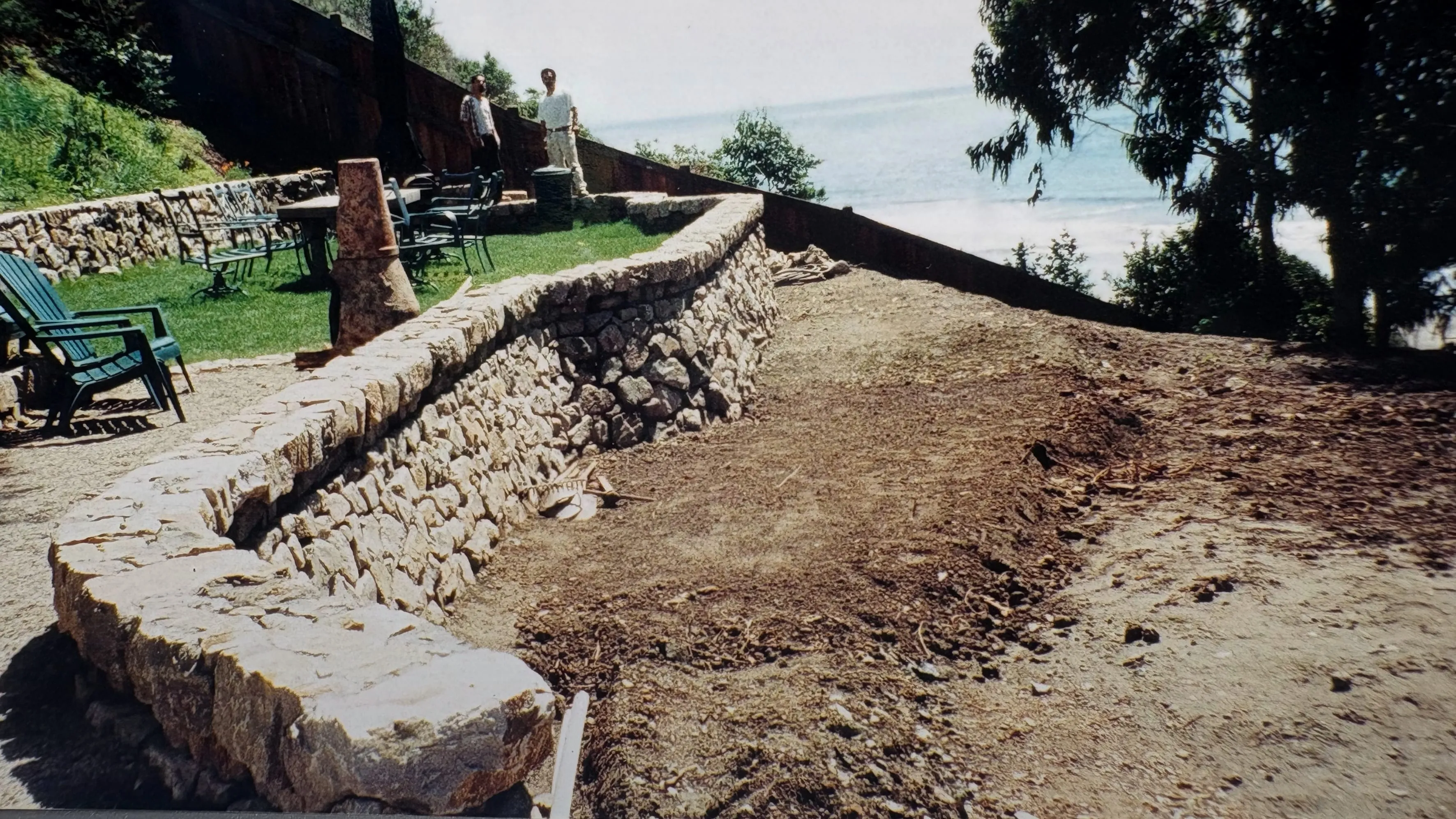 A hand-laid dry-stack stone retaining wall built by Reynoso's Stoneworks above the coast