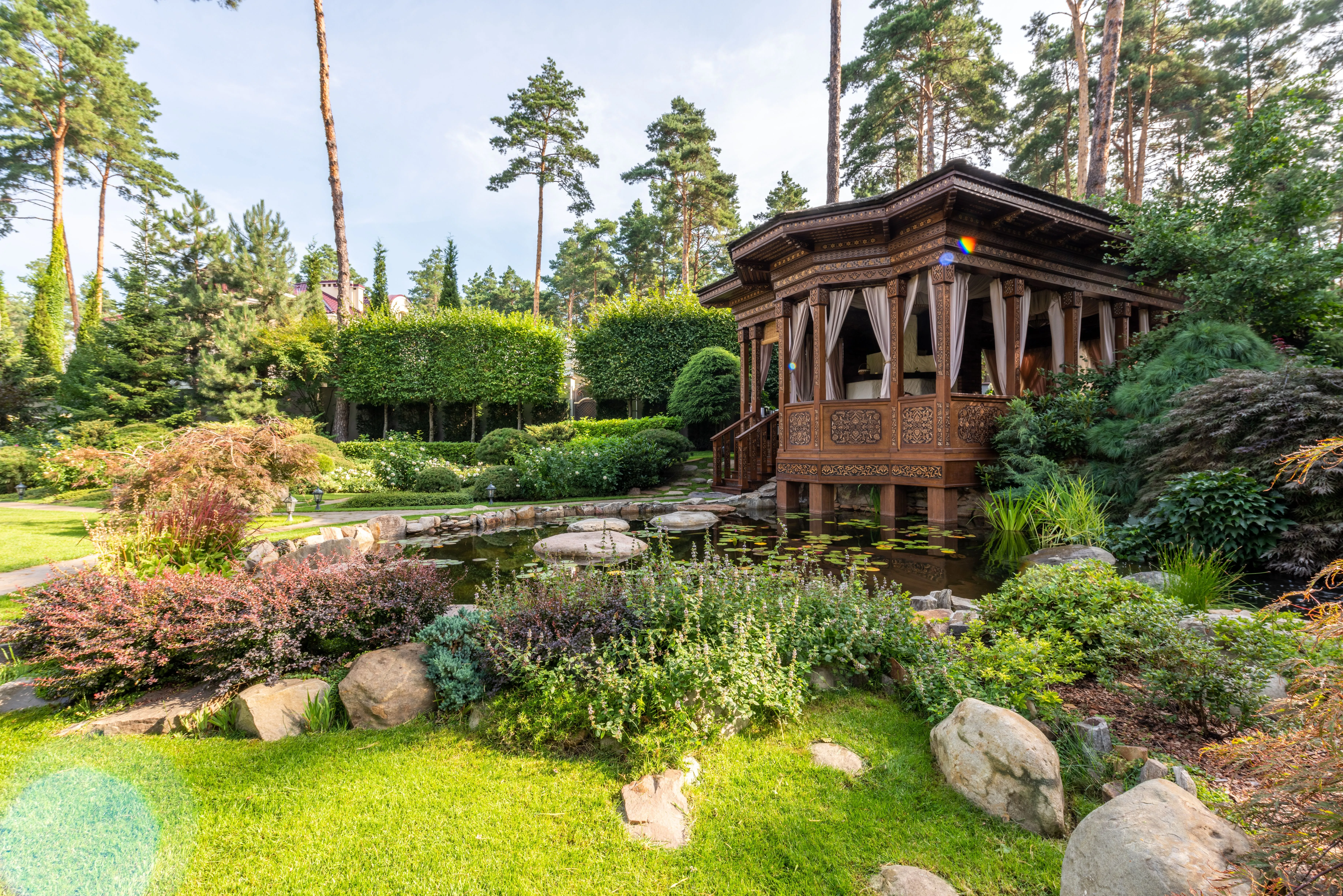 Garden gazebo beside a koi pond surrounded by mixed planting and rockery