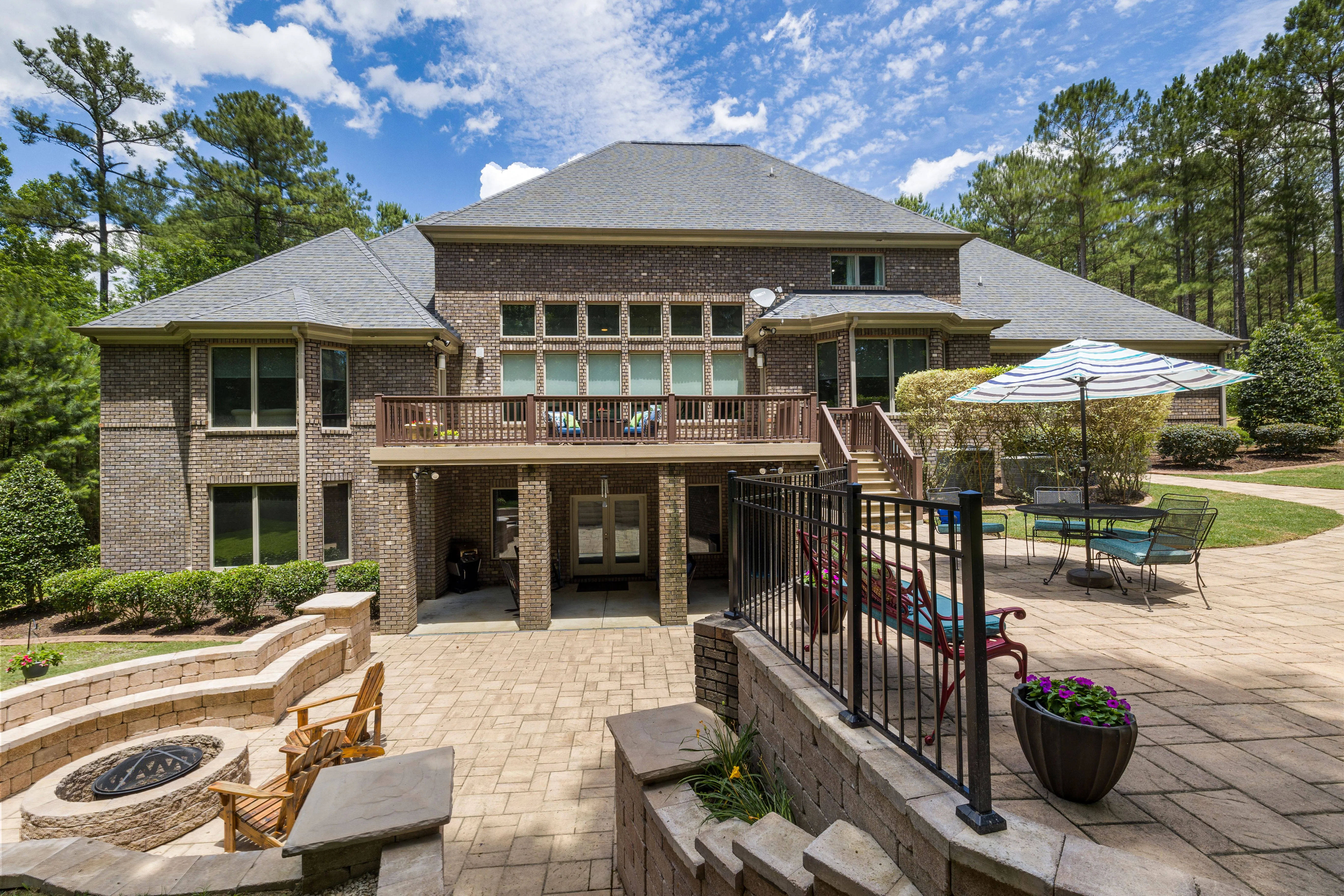 Brick home with a multi-level paver patio, fire pit and planted borders