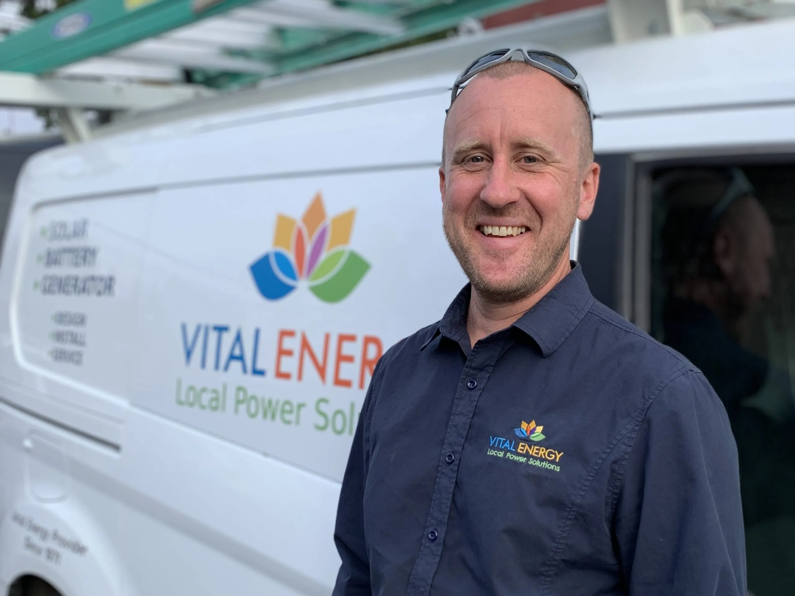 A Vital Energy team member in front of a branded company van